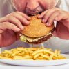 close up photo of man eating burger and french fries